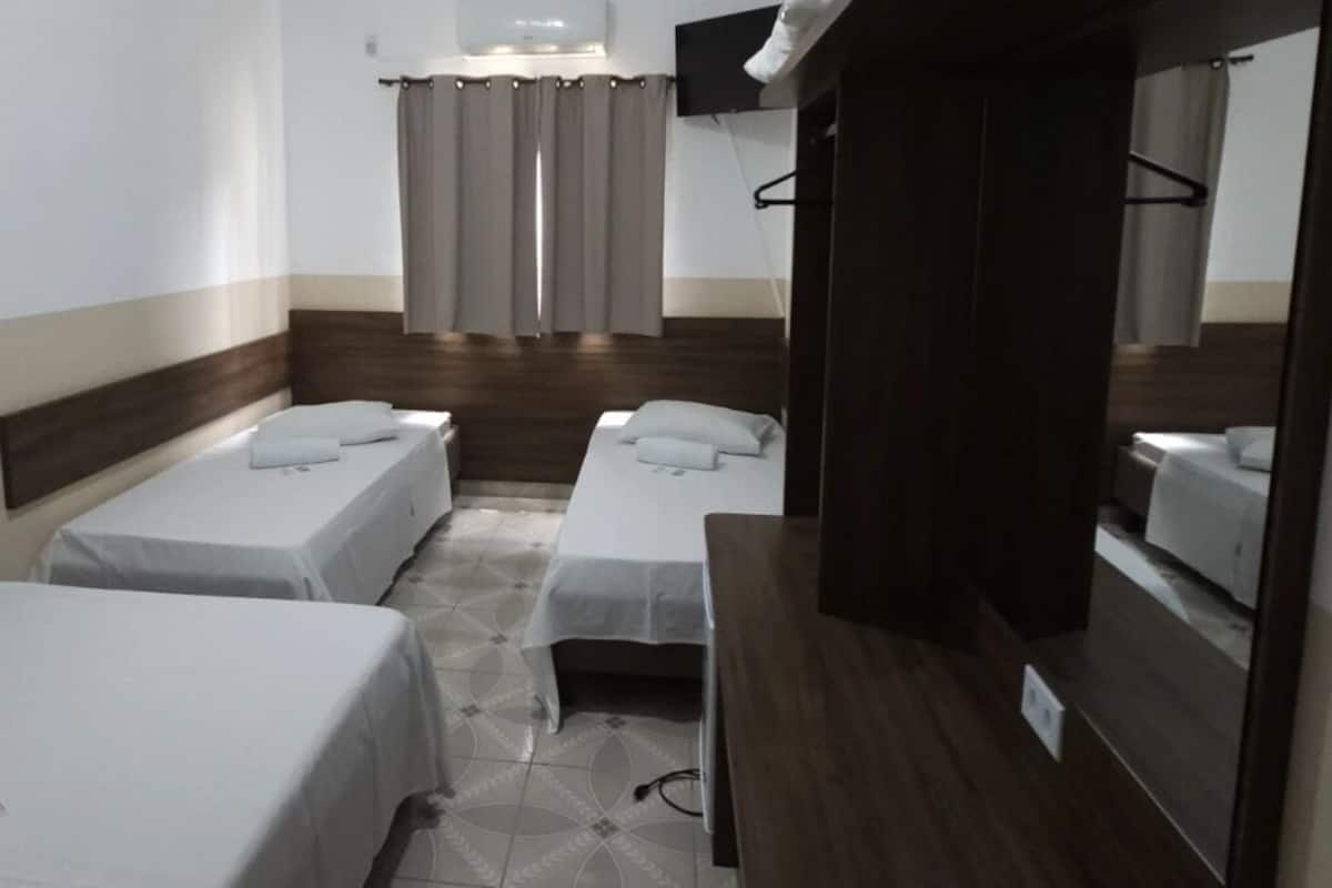 Ett hotellrum med två separata sängar, en sänggavel i trä, ett litet skrivbord och en spegel.