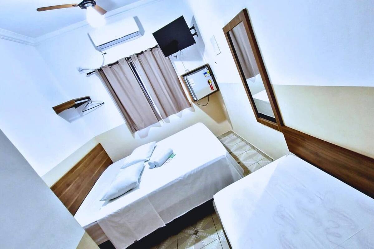 Ett hotellrum med två sängar, en takfläkt, en TV och ett litet bord med en spegel.