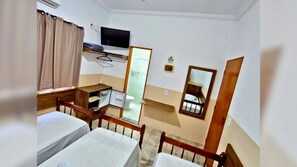 Une chambre d’hôtel avec deux lits, une télévision, un miroir et une petite table.