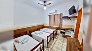A room with three single beds, a ceiling fan, an air conditioning unit, a television mounted on the wall, and a small table. - Pousada Bela Rainha (Aparecida)