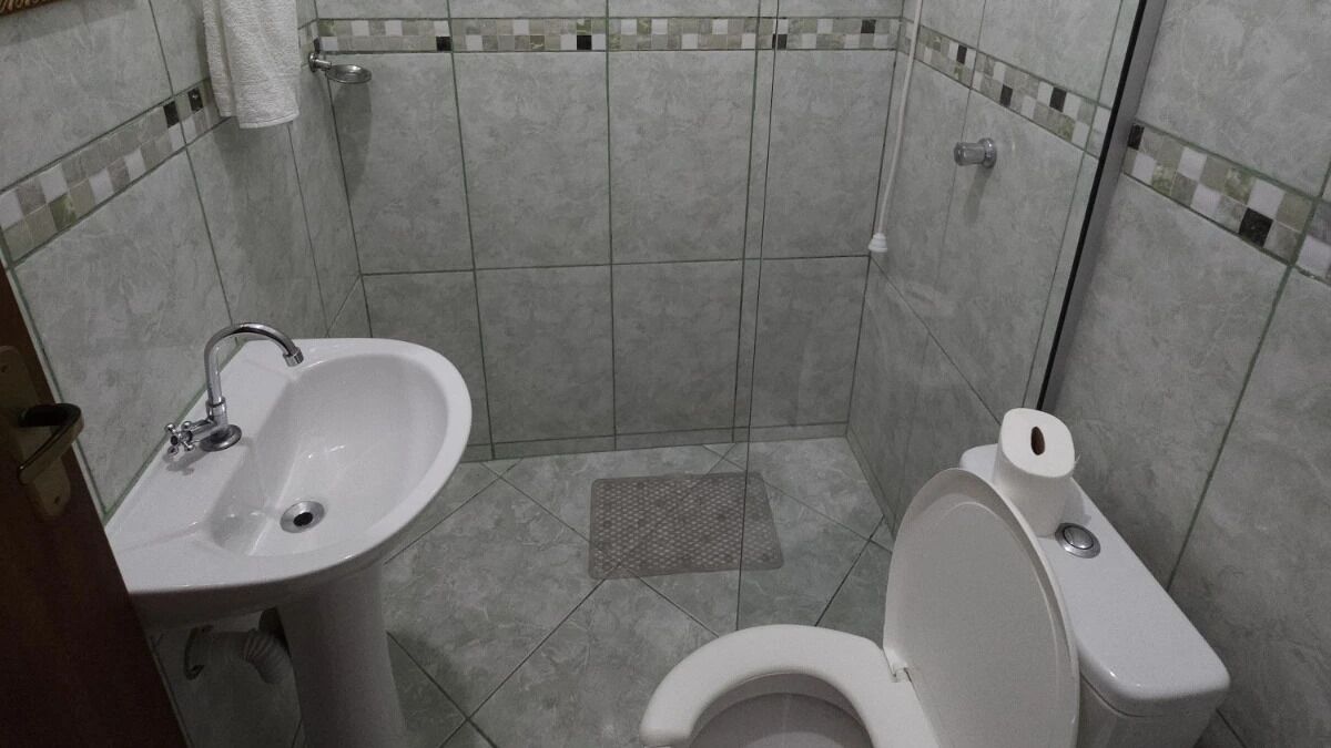 A small bathroom with a sink, toilet, and tiled walls.