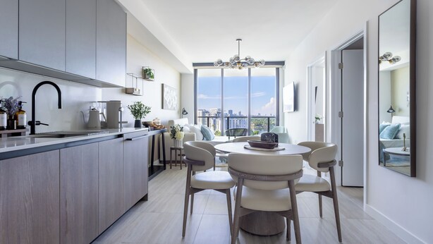 Een moderne keuken met een centraal eiland, een eethoek met een ronde tafel en stoelen, en grote ramen met uitzicht op de stad.