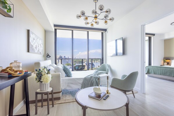 A modern living room with a large window, a round table, a sofa, and a chair.