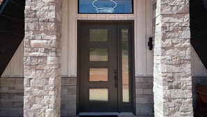 A stone-clad entrance with a dark door and a small window above it. - The Dome Home | 8 mins from Kanarra Falls (New Harmony)