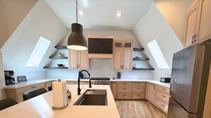 A modern kitchen with a central island, built-in appliances, and skylights. - The Dome Home | 8 mins from Kanarra Falls (New Harmony)