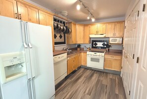A kitchen with wooden cabinets, a white refrigerator, a stove, a microwave, and a dishwasher. - Your Boulder Home Base, Walk to Pearl St, 2BR/2BA + Parking! (Boulder)