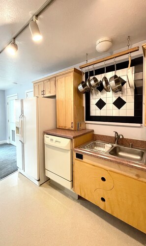 A kitchen with wooden cabinets, a white refrigerator, a dishwasher, and a sink with a faucet.