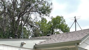 Ein kleines Haus mit Terrasse, einem Tisch mit Stühlen und einer blauen Tür.