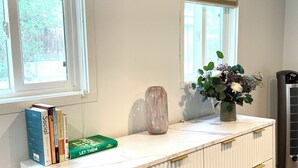 Ein weißer Kommode mit goldfarbenen Griffen, eine Vase mit Blumen und Bücher darauf.