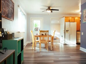 A modern kitchen with wooden cabinets, a white refrigerator, and a dining area with a wooden table and chairs. - Your Boulder Home Base, Walk to Pearl St, 2BR/2BA + Parking! (Boulder)