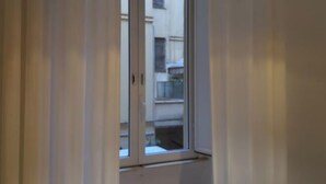 A view through a window with a white frame, revealing a building with multiple balconies and a white exterior. - Gracchi 278 - The Italian Stay Collection (Rome)