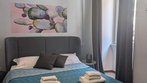 A neatly made bed with a blue quilt, pillows, and folded towels on a headboard. - Gracchi 278 - The Italian Stay Collection (Rome)