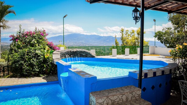 A swimming pool with a view of mountains, surrounded by greenery and a pergola. - Room just 20 minutes from the airport. (Alajuela)