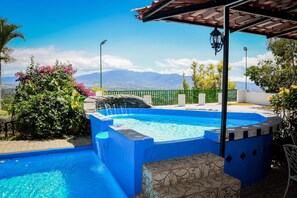 A swimming pool with a view of mountains, surrounded by greenery and a pergola. - Room just 20 minutes from the airport. (Alajuela)