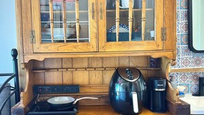 Una cocina de madera con estufa, hervidor y cafetera.