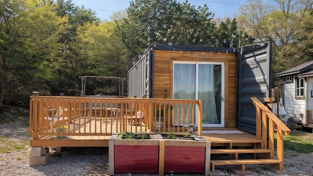Una cabaña de madera pequeña con un balcón y una puerta corrediza.
