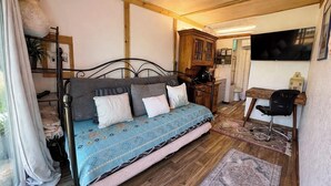 Un dormitorio con cama, escritorio, televisión y ventana.