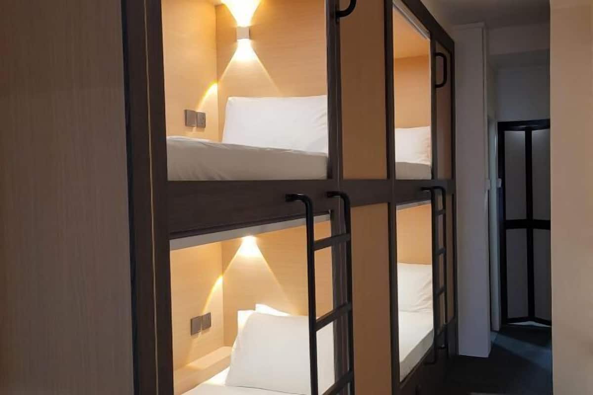 Une chambre d’hôtel avec un lit superposé, une lampe de chevet et une porte donnant sur une autre pièce.