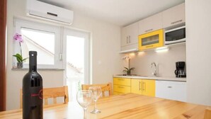 A kitchen with yellow cabinets, a microwave, and a wine bottle on the table.