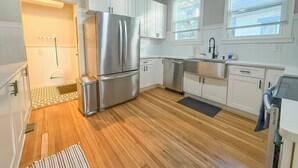 Una cocina moderna con armarios blancos, electrodomésticos de acero inoxidable y piso de madera.
