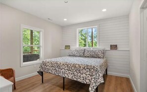 A bedroom with a bed, two windows, a small table, and a chair. - Quiet Cove Getaway gourmet style (Camdenton)
