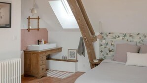 A bedroom with exposed wooden beams, a skylight, a bed, a dresser, a vanity, and a radiator. - Le Petit Civry - SAINT JULIEN DE CIVRY (SAINT JULIEN DE CIVRY)