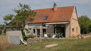 A two-story house with a red-tiled roof, a stone wall, and a covered patio area with outdoor furniture. - Le Petit Civry - SAINT JULIEN DE CIVRY (SAINT JULIEN DE CIVRY)