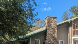 Une maison à deux étages avec une cheminée en pierre, un porche couvert et une pelouse bien entretenue.