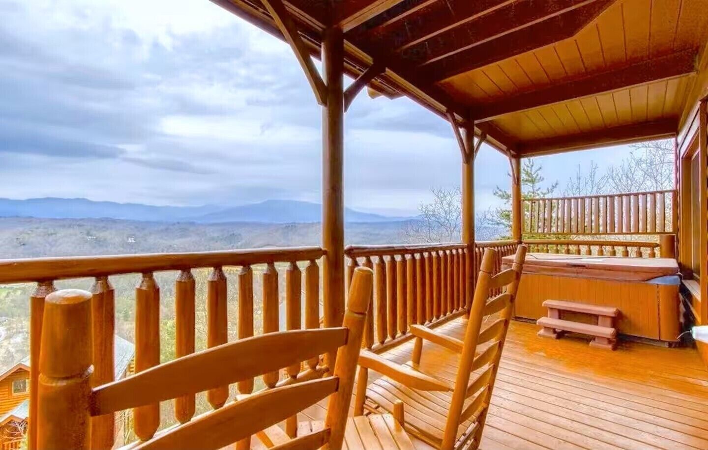 A wooden deck with chairs and a bench, overlooking a mountainous landscape.
