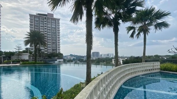 A swimming pool with a curved edge, palm trees, and a tall building in the background. - Casa Budi Dwiputra 15 Putrajaya (Putrajaya)