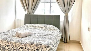 A neatly made bed with a patterned bedspread, a headboard, and curtains on a window. - Casa Budi Dwiputra 15 Putrajaya (Putrajaya)