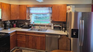 A kitchen with wooden cabinets, a stainless steel refrigerator, a microwave, a dishwasher, and a ceiling fan.
