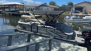 Un bateau était amarré dans une marina, avec un espace de repos abrité, un moteur hors-bord Yamaha et un autre bateau amarré en arrière-plan.