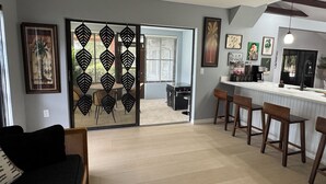 Une cuisine moderne dotée d’un bar, d’un coin repas avec un canapé et d’une vue sur l’extérieur grâce à une porte à motifs.