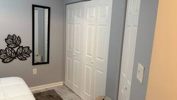 A bedroom with a bed, a fluffy rug, a mirror, and a closet with two doors.