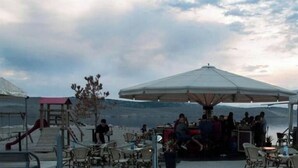 An outdoor seating area with tables and umbrellas, overlooking a body of water. - 14Person Combination Apartment 4 Apartments Combined (Jadranovo)