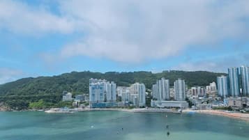 A coastal cityscape with high-rise buildings, a beach, and a hilly backdrop.