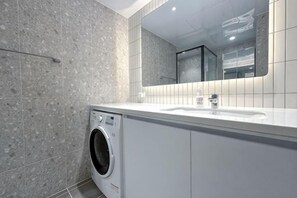 Un baño moderno con lavadora, lavamanos y espejo.