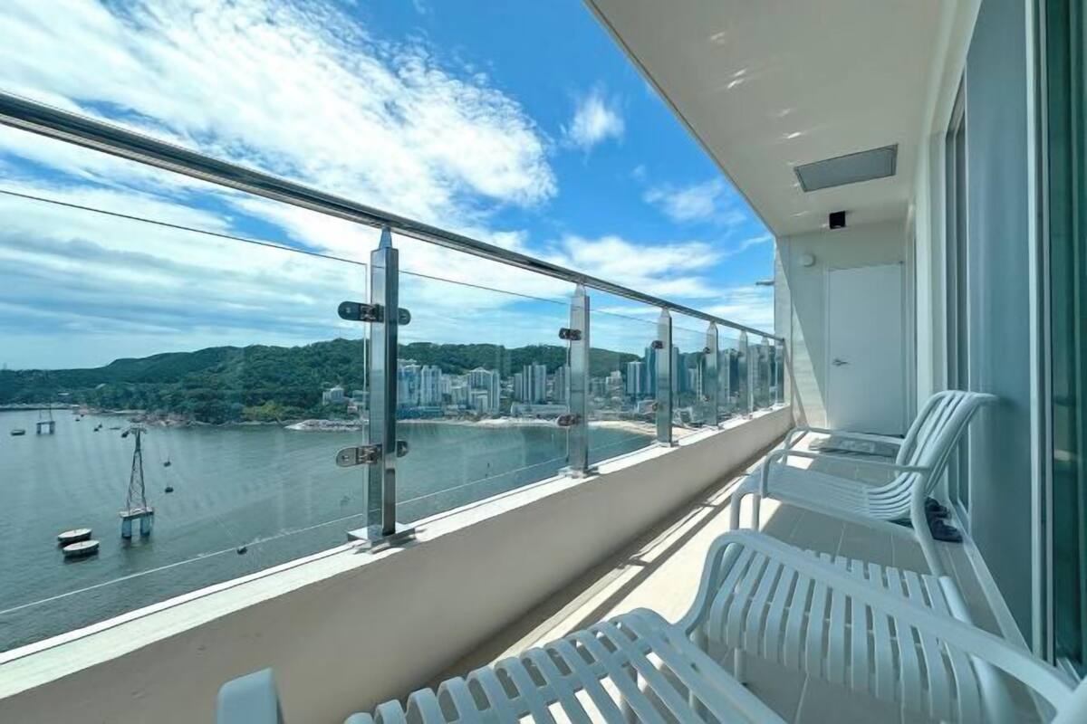 A balcony with a view of a body of water, chairs, and a railing.