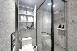 A bathroom with a toilet, shower, and glass-enclosed shower stall. - The First Ocean Songdo (Busan)