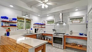 Une cuisine moderne dotée d’un îlot central, d’un four encastré et d’un ventilateur de plafond.