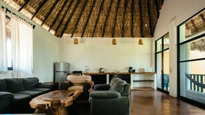 A spacious living area with a thatched ceiling, a large wooden coffee table, and comfortable seating. - Bungalows Oasis (Brisas de Zicatela)