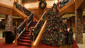 Una imponente escalera con un gran árbol de Navidad, barandillas de madera y pilares de piedra.