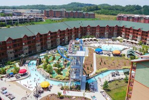 A hotel with a large pool area, a water slide, and multiple levels of balconies. - Wilderness at the Smokies – River Lodge Suites (Sevierville)