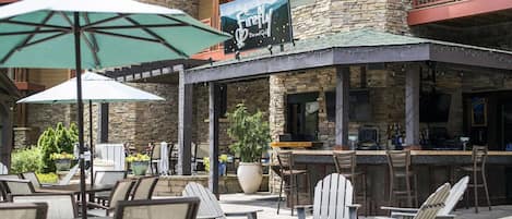 Un espacio al aire libre con mesas, sillas y sombrillas en un restaurante llamado "The Firefly Bar and Grill".