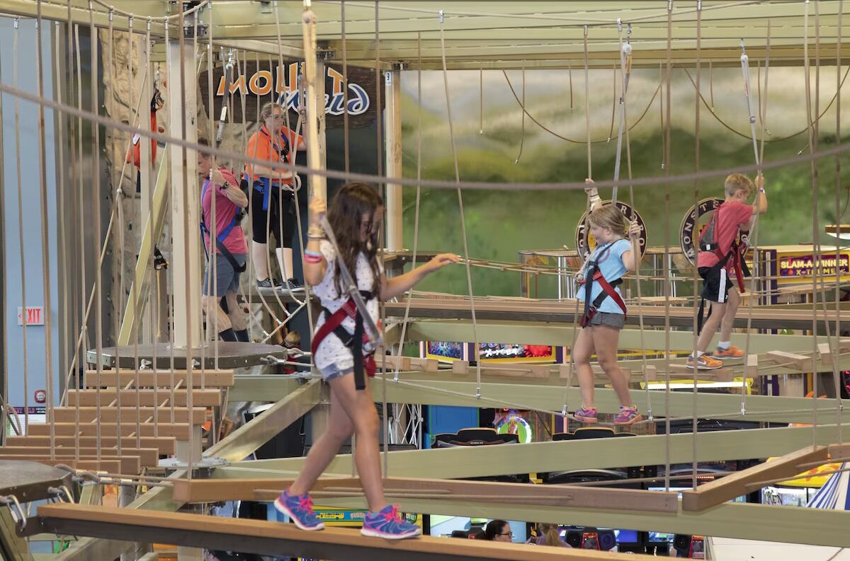 Een groep mensen op een houten hindernisbaan, met een bord waarop 'Monster' staat.