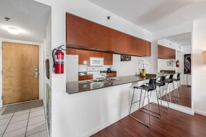 Una cocina moderna con una isla integrada, electrodomésticos de acero inoxidable y un extintor de incendios en la pared.