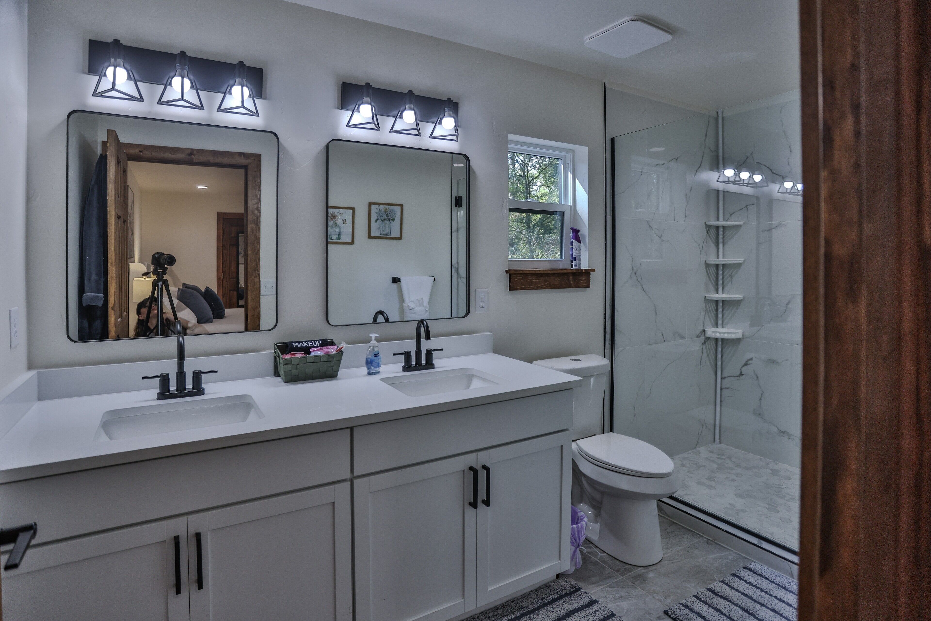 A modern bathroom with dual sinks, a large mirror, and a glass shower enclosure.