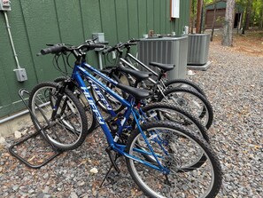 Bicicletas estacionadas sobre una superficie de grava, con un muro verde y un edificio al fondo.