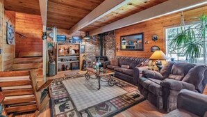 A cozy cabin interior with a wooden ceiling, a fireplace, a sofa, and a coffee table.